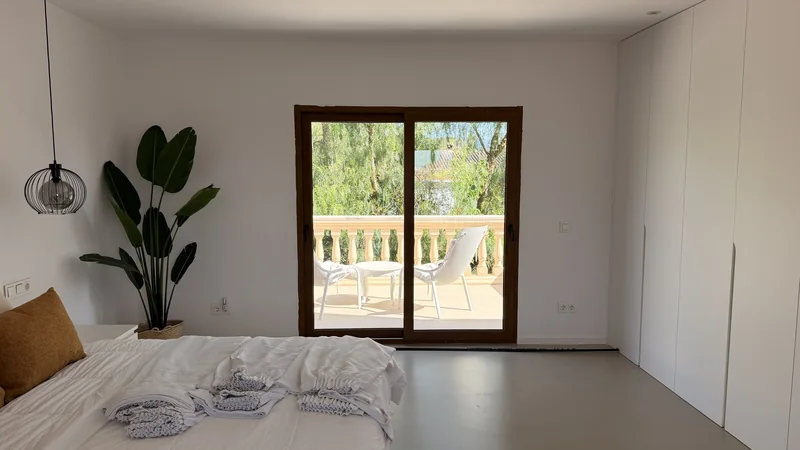 El dormitorio principal antes de las cortinas: puerta a la terraza y paredes blancas sin vestir
