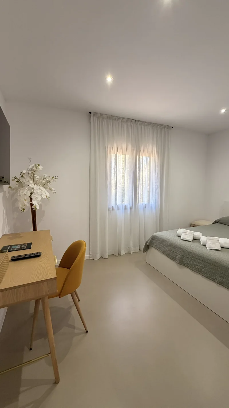 Dormitorio con escritorio de madera y visillo blanco a contraluz