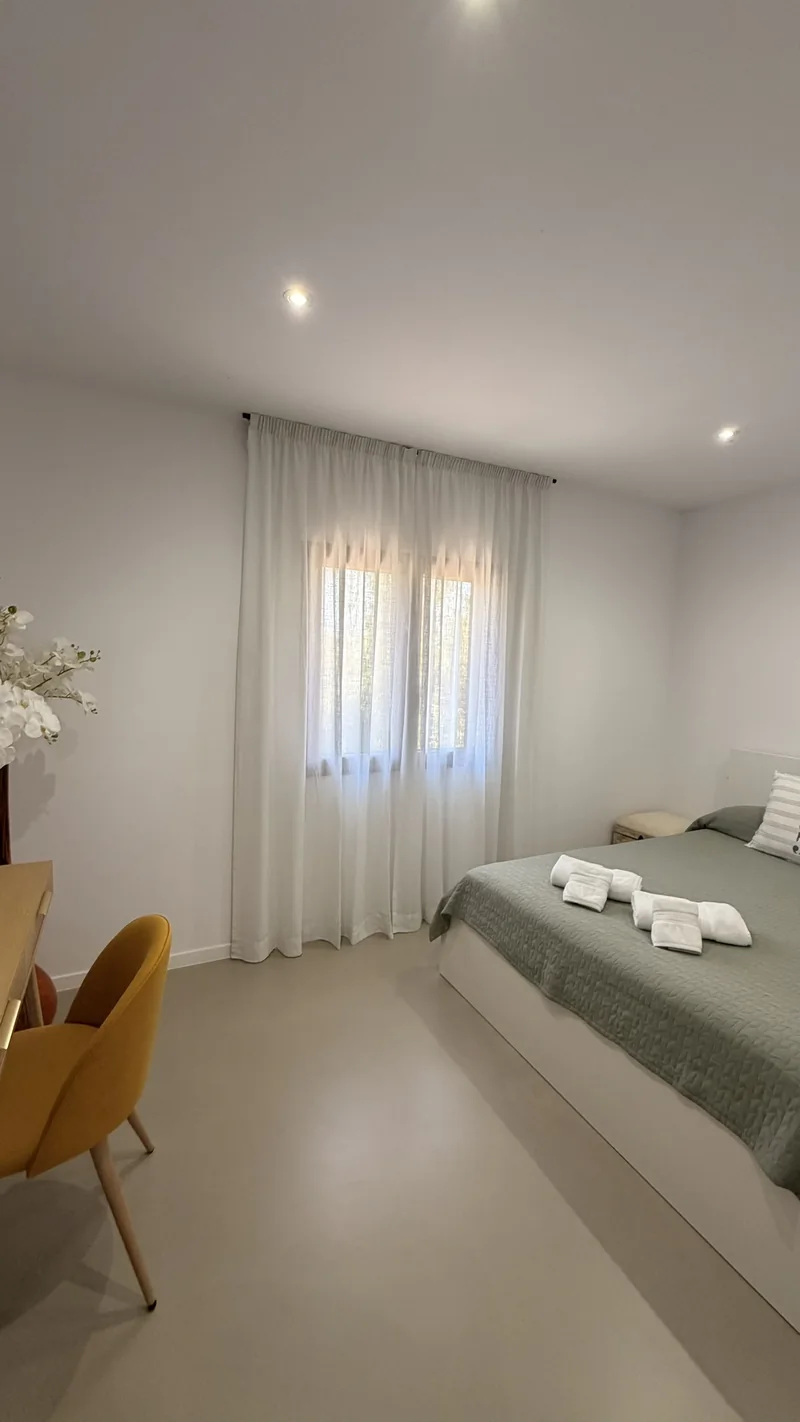Dormitorio con visillo blanco de lino delante de la ventana