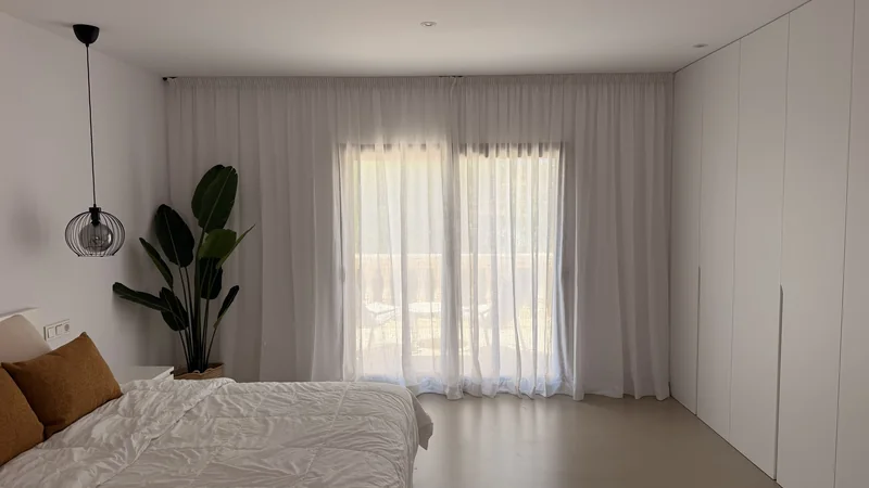 Dormitorio con visillos blancos de lino en la finca Can Ferragut, en Ponent