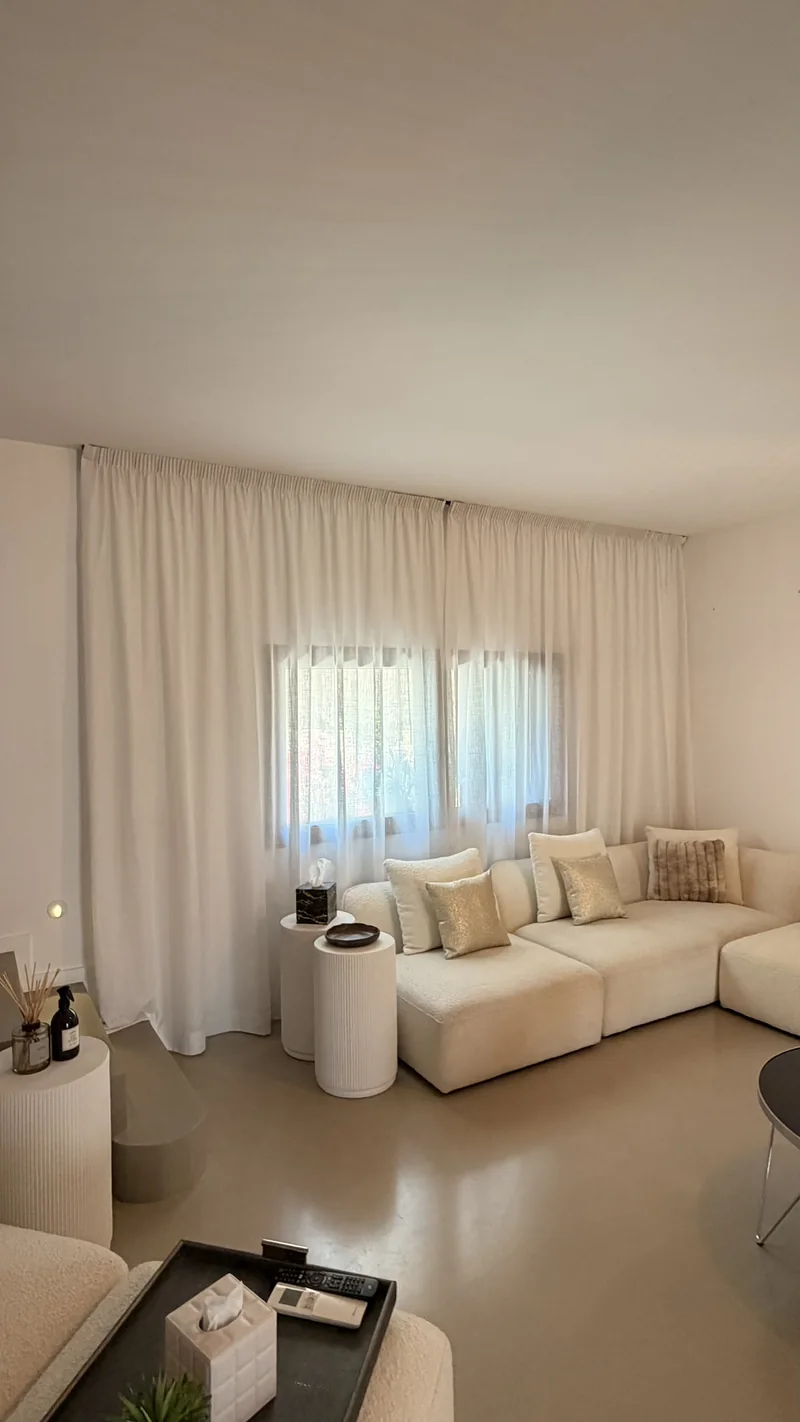 Salón con visillos blancos de lino tamizando la luz sobre el sofá