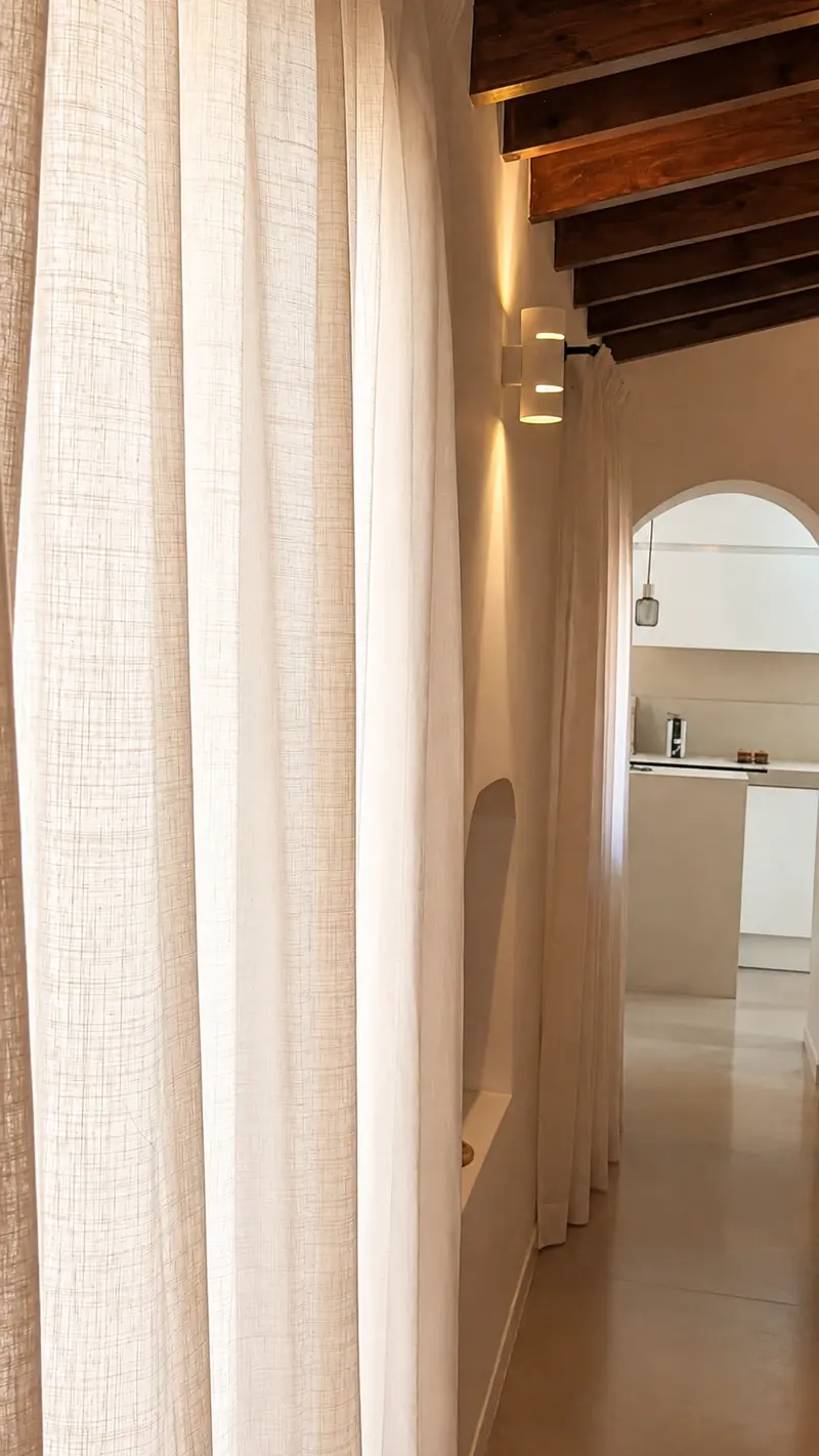 Visillo blanco de lino junto a un arco con vistas a la cocina