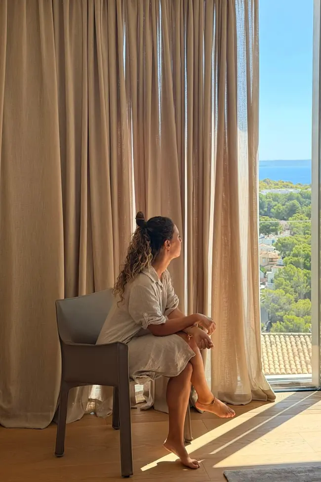 Dormitorio con cortinas de suelo a techo en tono arena y vistas al mar