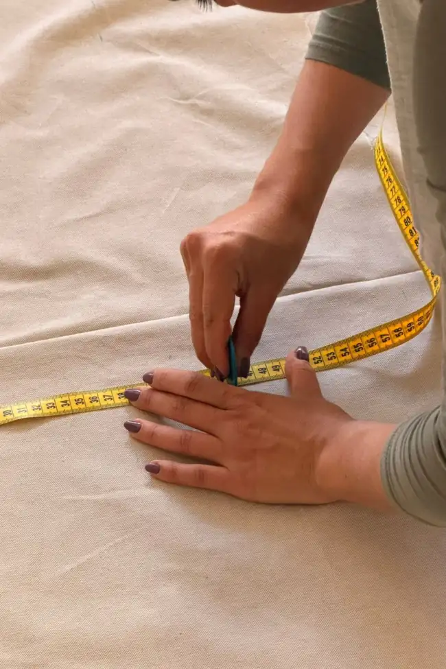 Marcando con tiza y cinta métrica una tela antes de cortarla para una cortina a medida