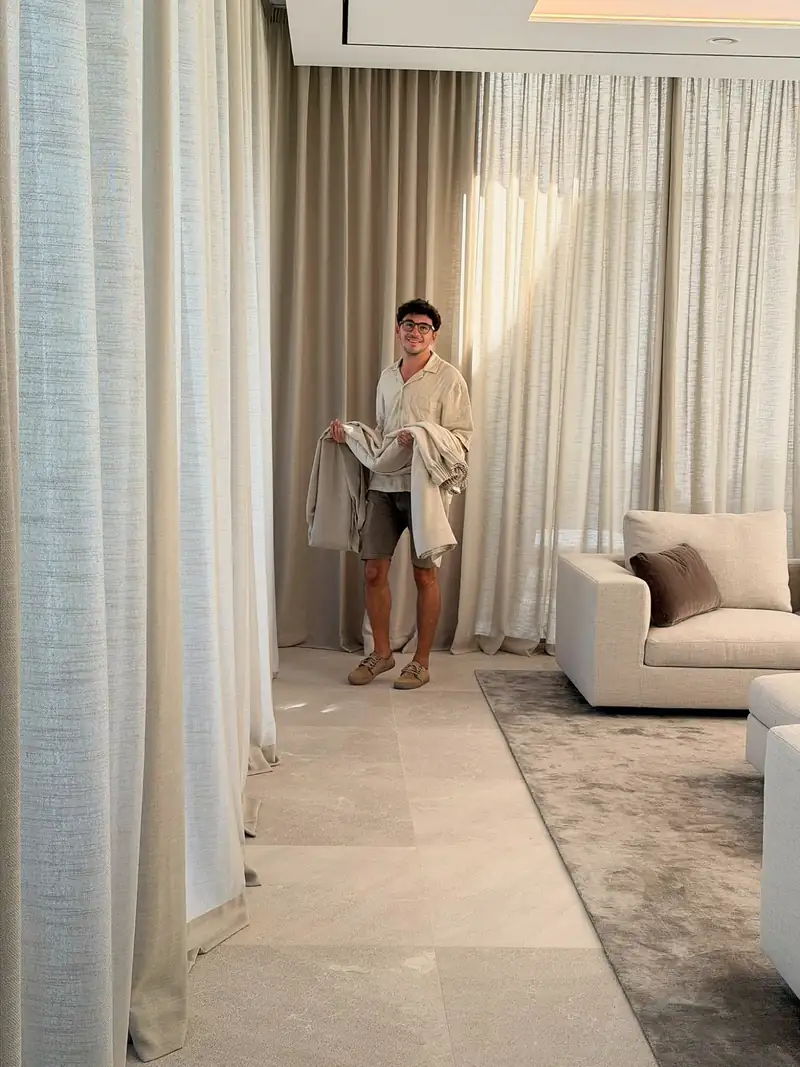 Integrante del equipo de DECORT MARUCC con cortinas en brazos durante una instalación, junto a visillos de suelo a techo ya colgados