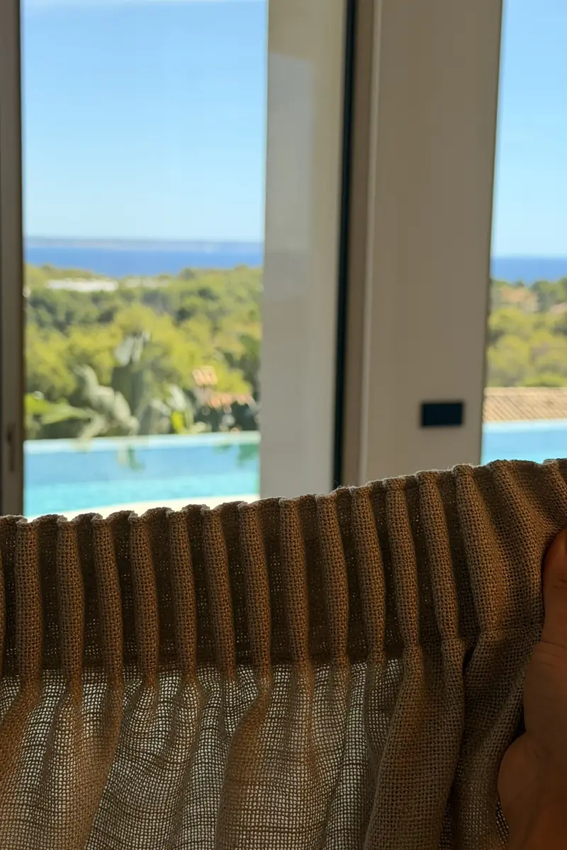 Detalle del cabezal fruncido del visillo con el mar y la piscina al fondo