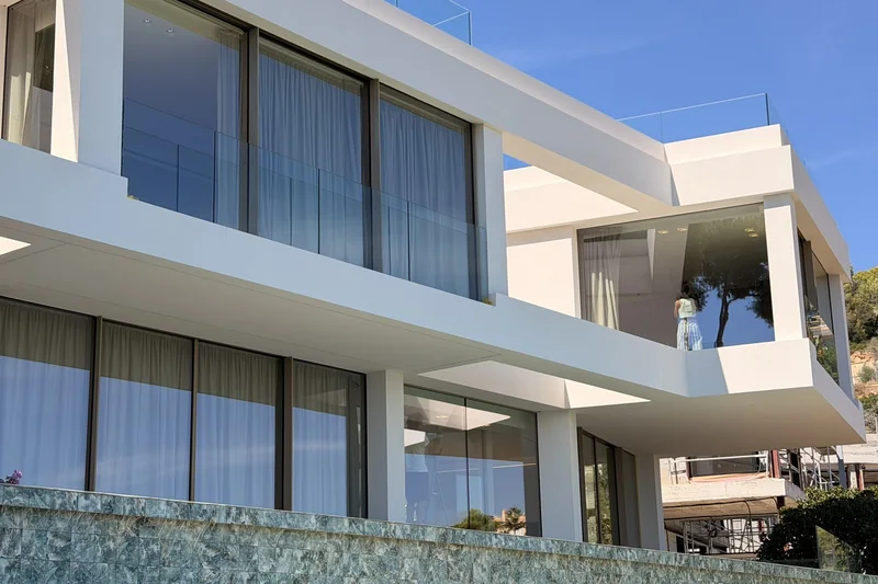 Fachada blanca de la villa en Portals Nous con grandes ventanales y terrazas en las dos plantas