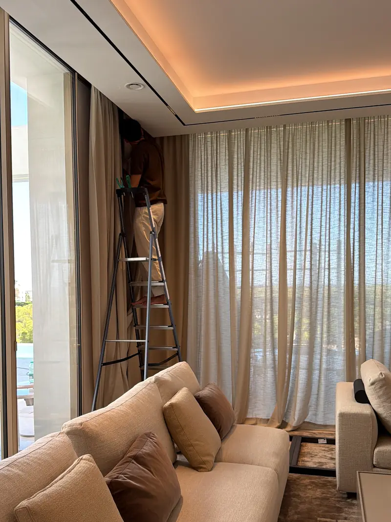 Instalador sobre una escalera montando el visillo de gran formato en el salón