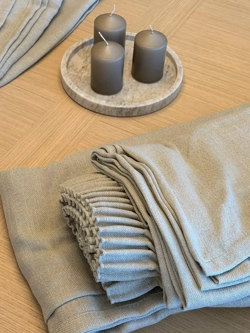 Detalle de muestras de tejido plegadas en tonos piedra junto a unas velas
