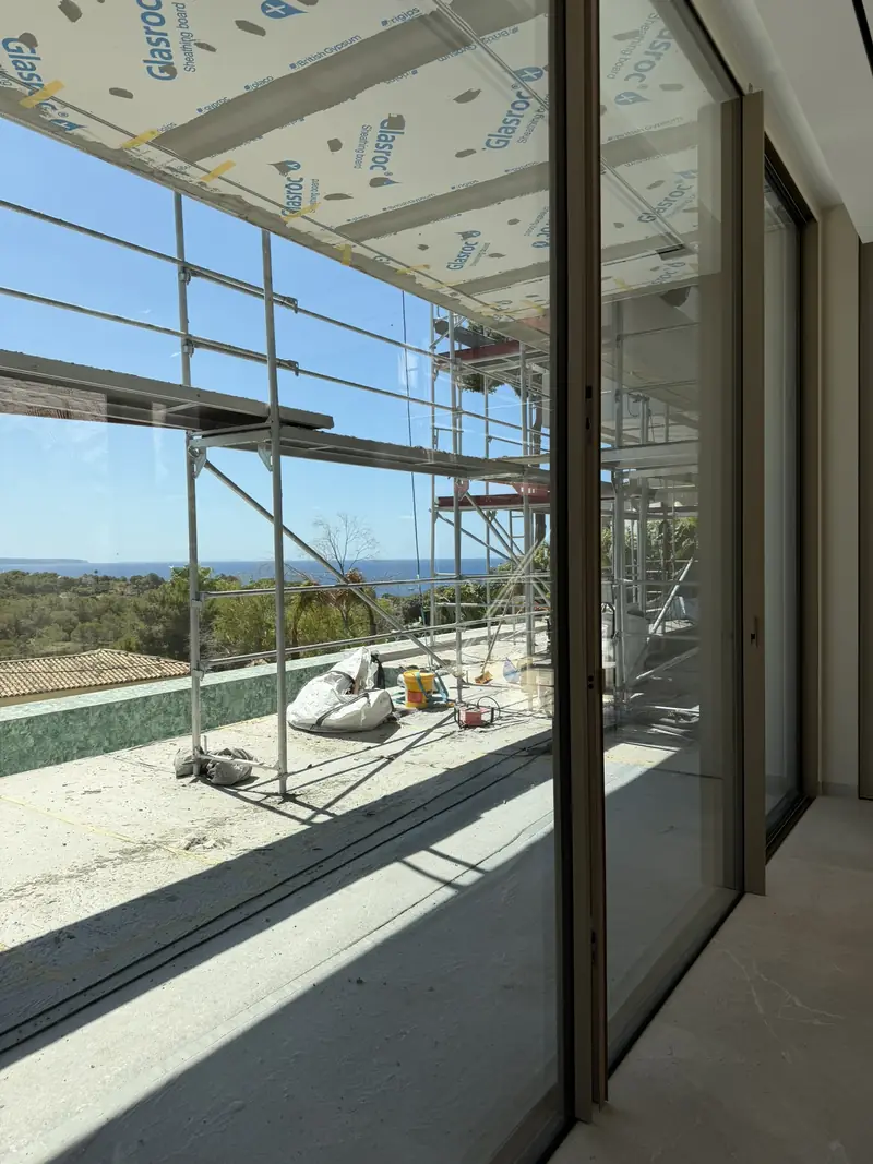 La vivienda en obra, con andamios en la fachada y los ventanales ya colocados