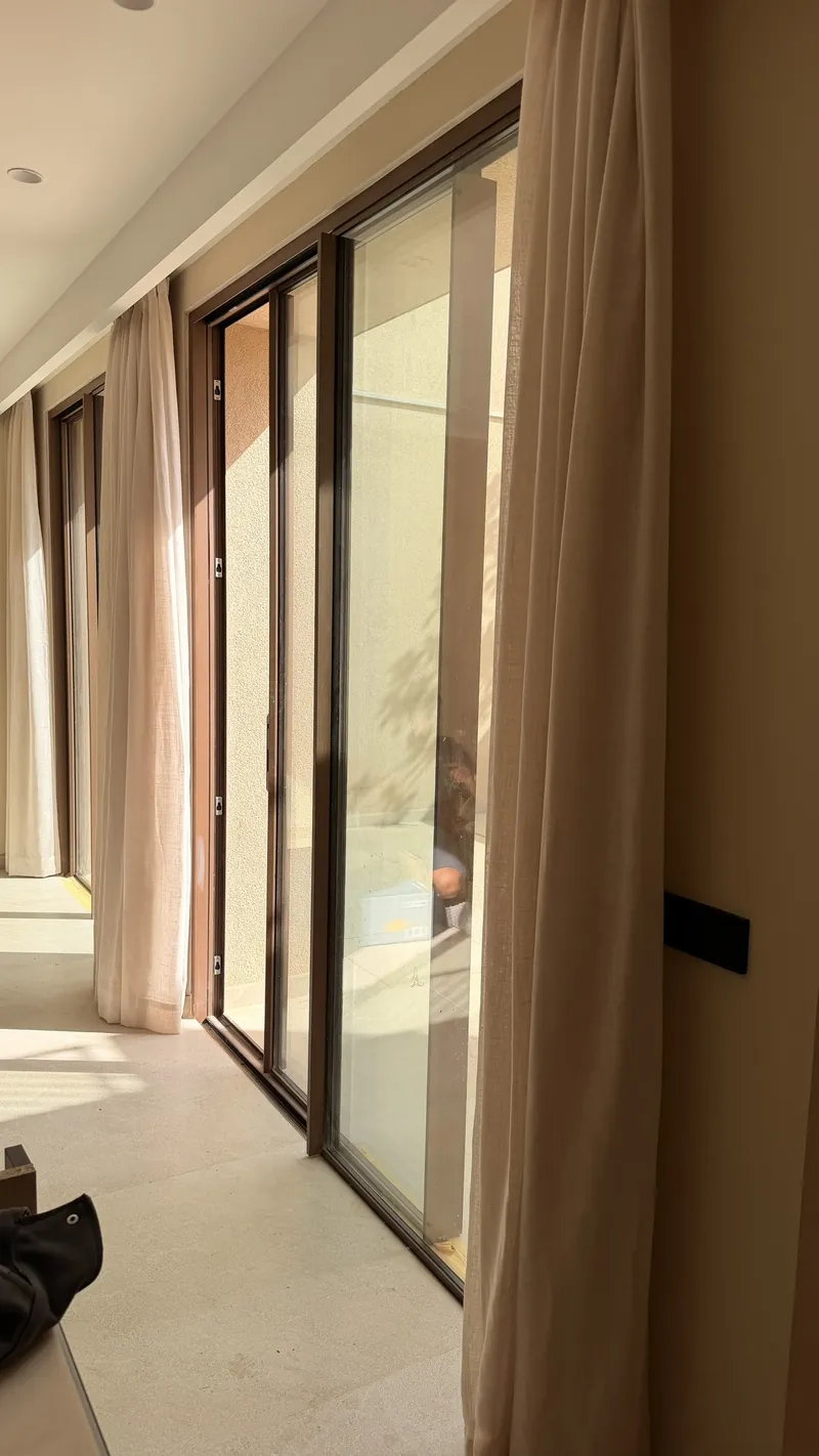 Comedor con ventanales de suelo a techo vestidos con visillo de lino en mezcla