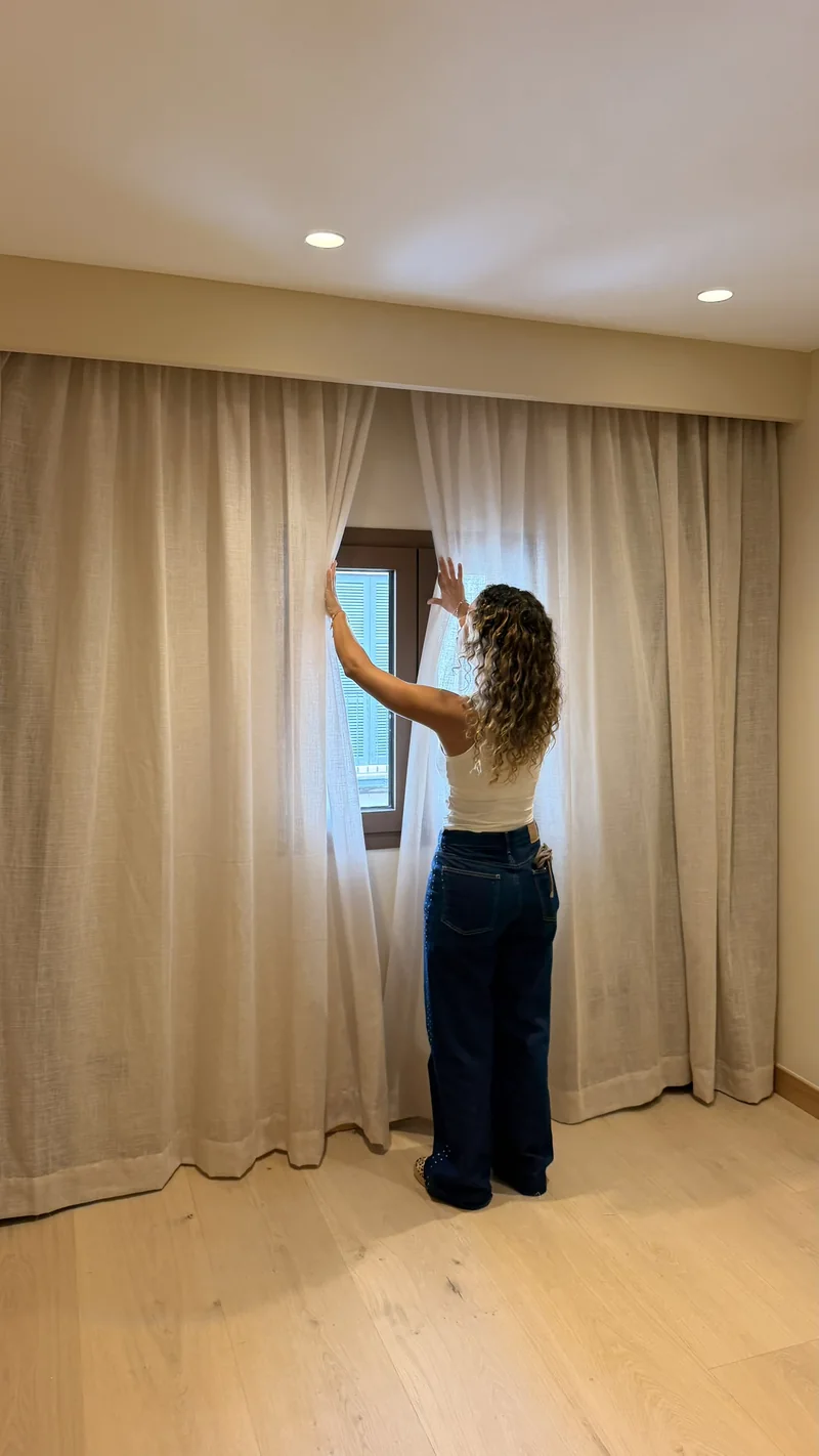Dormitorio con visillo de lino en mezcla delante de la ventana y cortina blackout recogida