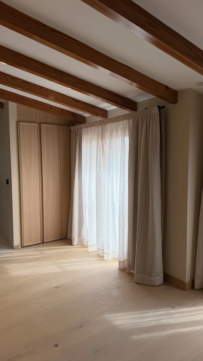 Dormitorio con techo inclinado de vigas y cortinas de suelo a techo