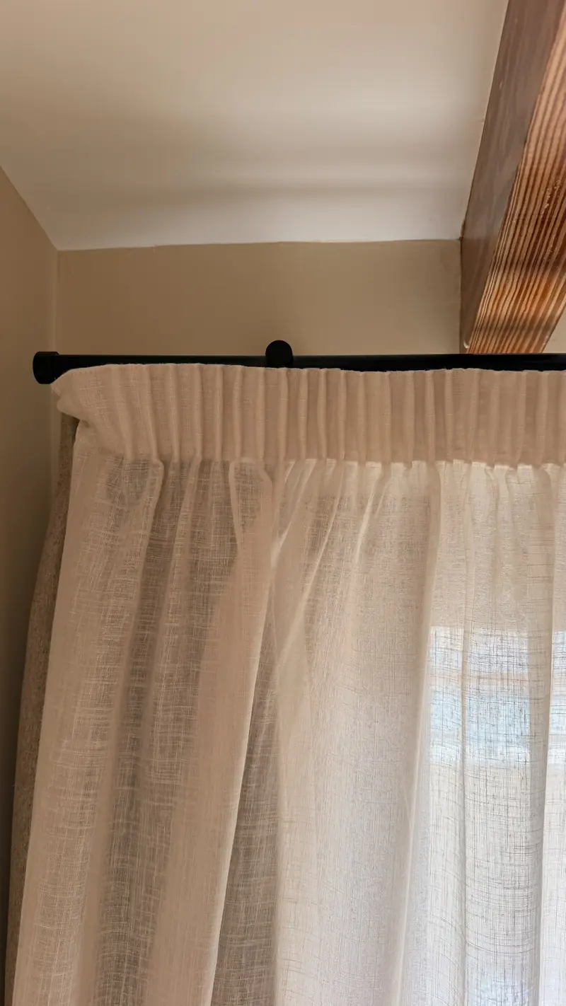 Riel negro a pared con soporte doble bajo un techo de vigas vistas
